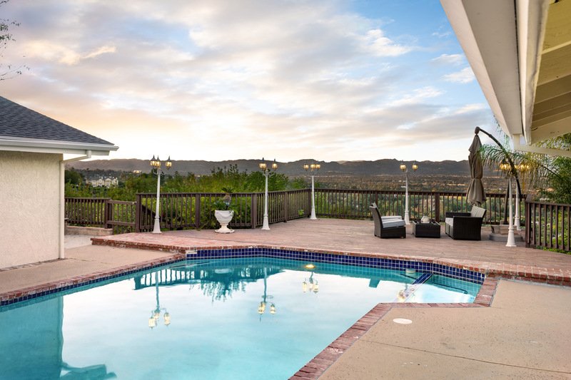 Una piscina al aire libre con asientos en el patio e iluminación.
