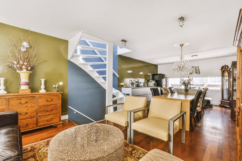 Diseño interior contemporáneo de estilo minimalista de un luminoso apartamento tipo estudio con mesa y sillas de madera en la zona de comedor entre la cocina abierta y la sala de estar con paredes blancas y suelo de parquet Casas Velaris.